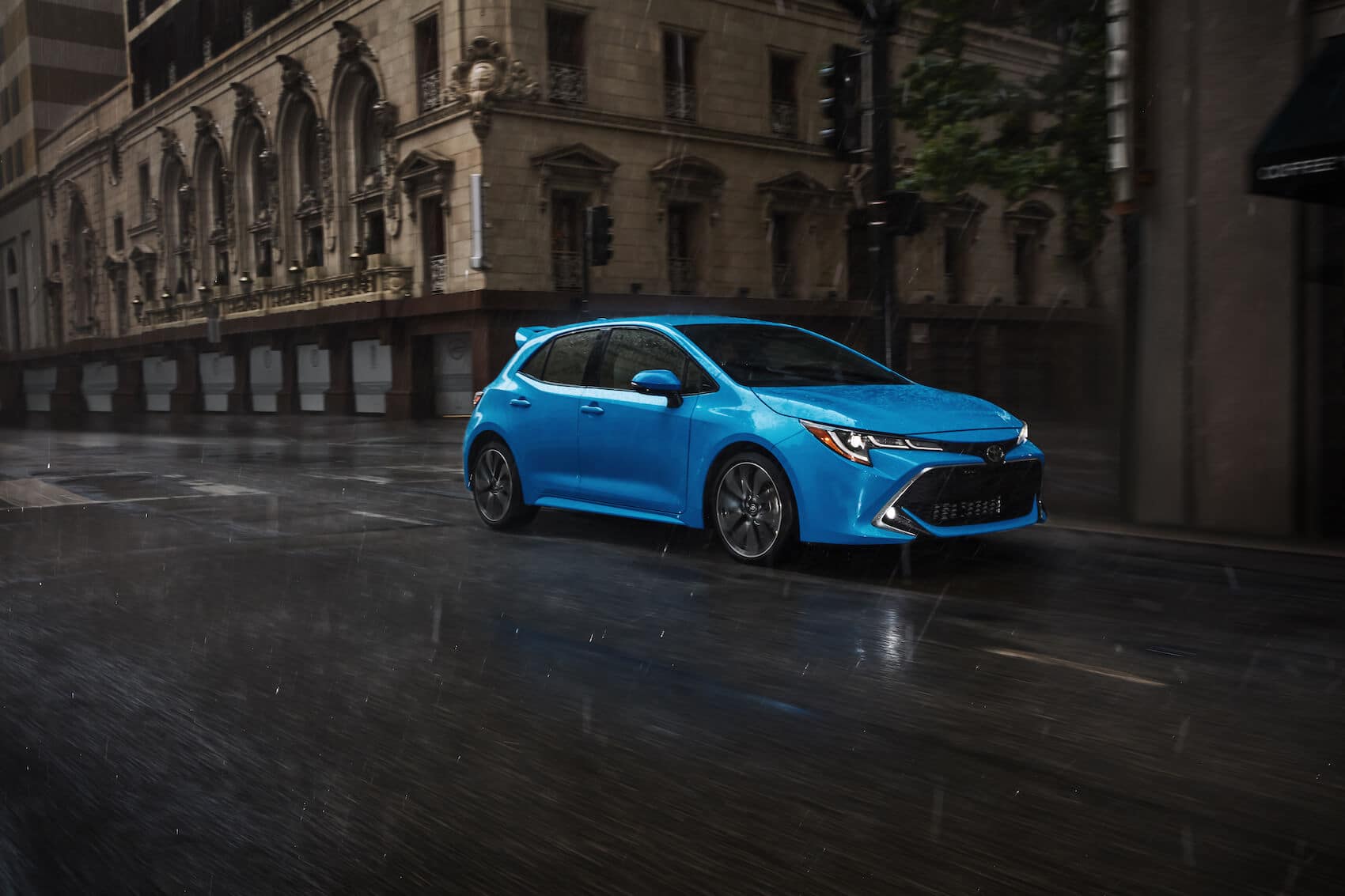 Toyota Corolla driving in the rain through a city